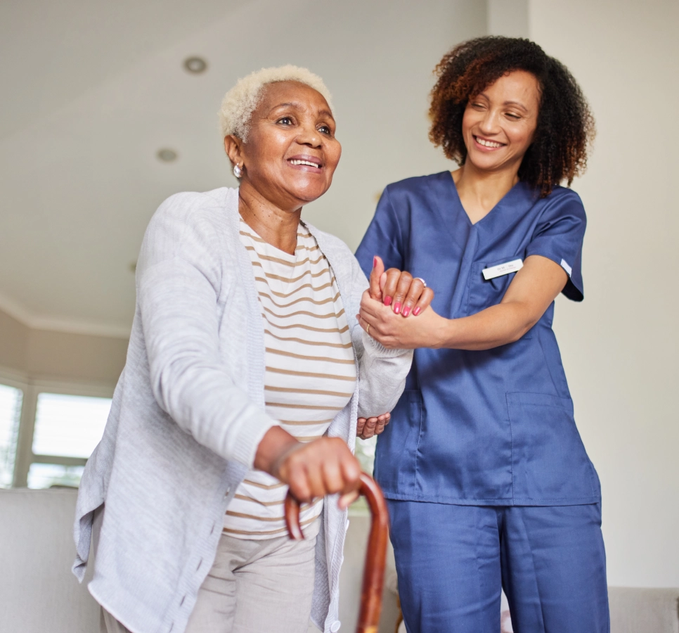 Elderly woman assisted by smiling caregiver.
