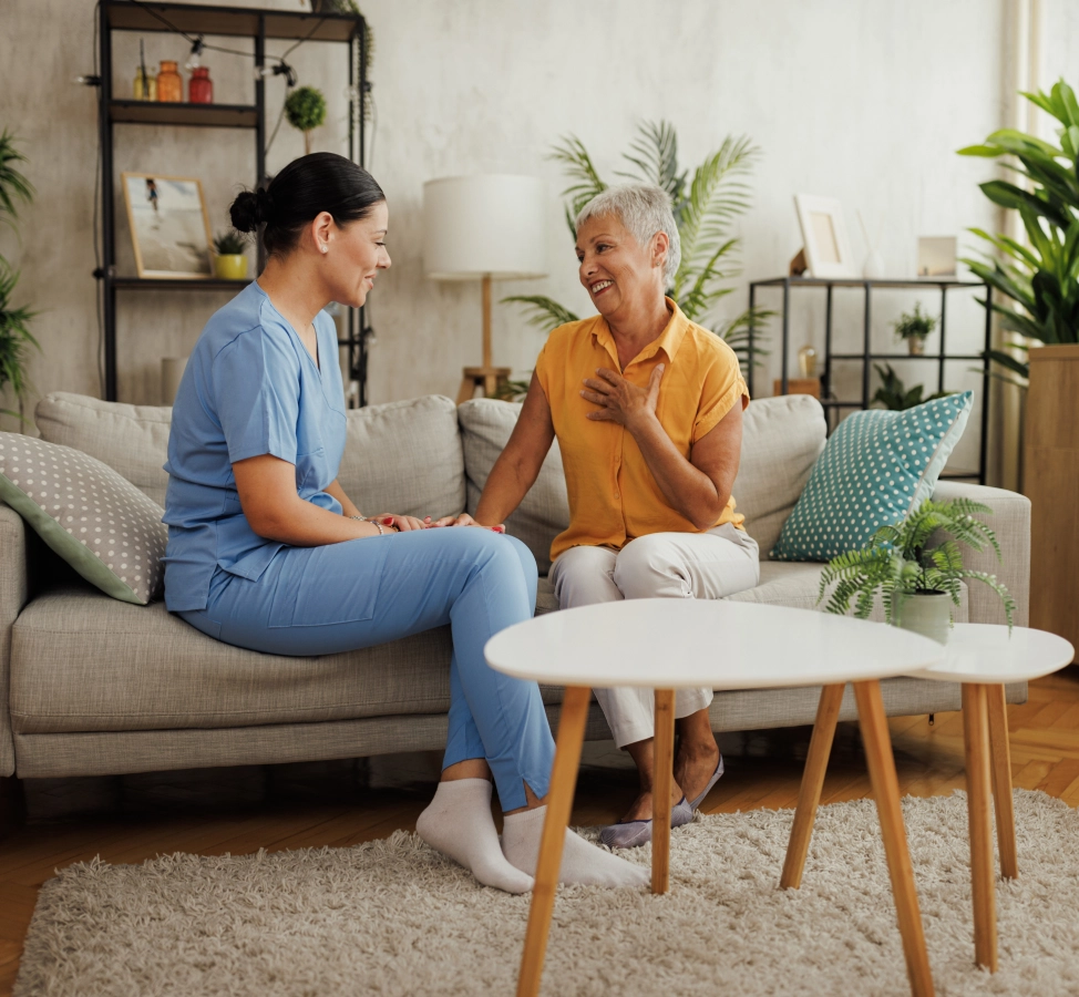 Nurse and elderly woman talking on sofa.