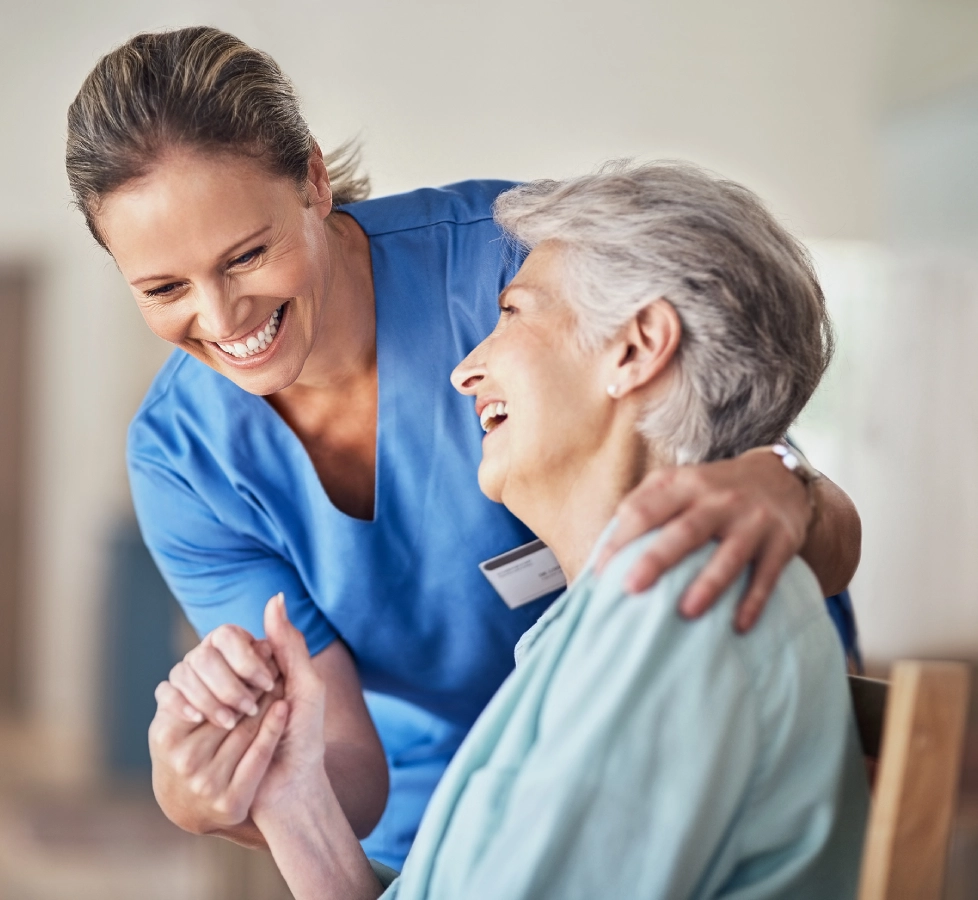 Nurse smiling with elderly woman in wheelchair.