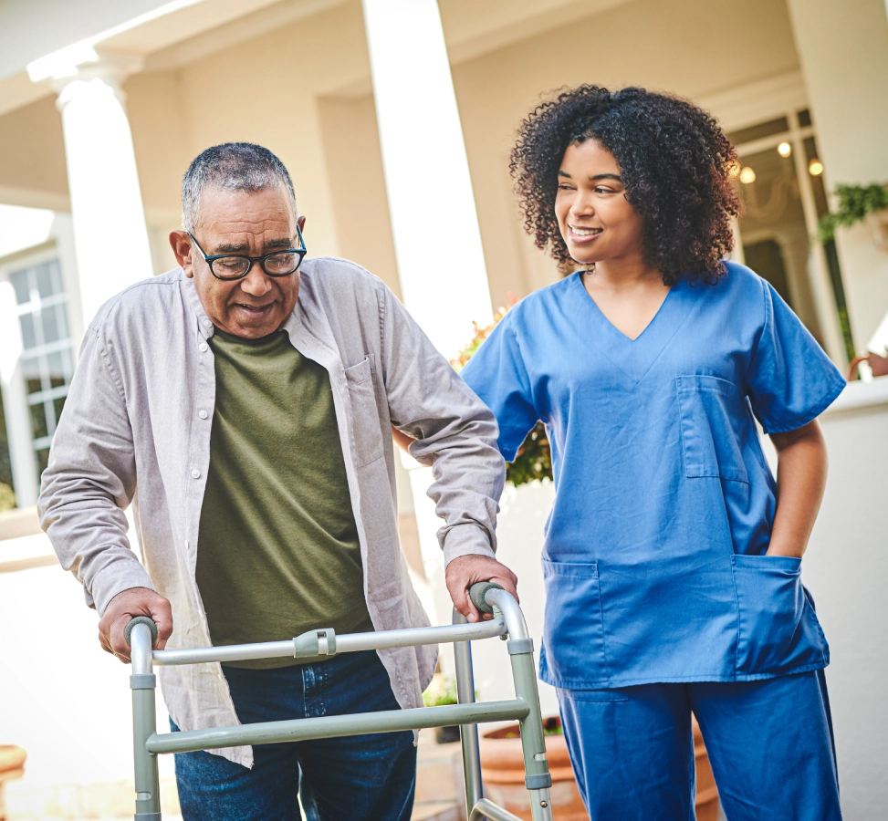 Elderly man with walker assisted by nurse.