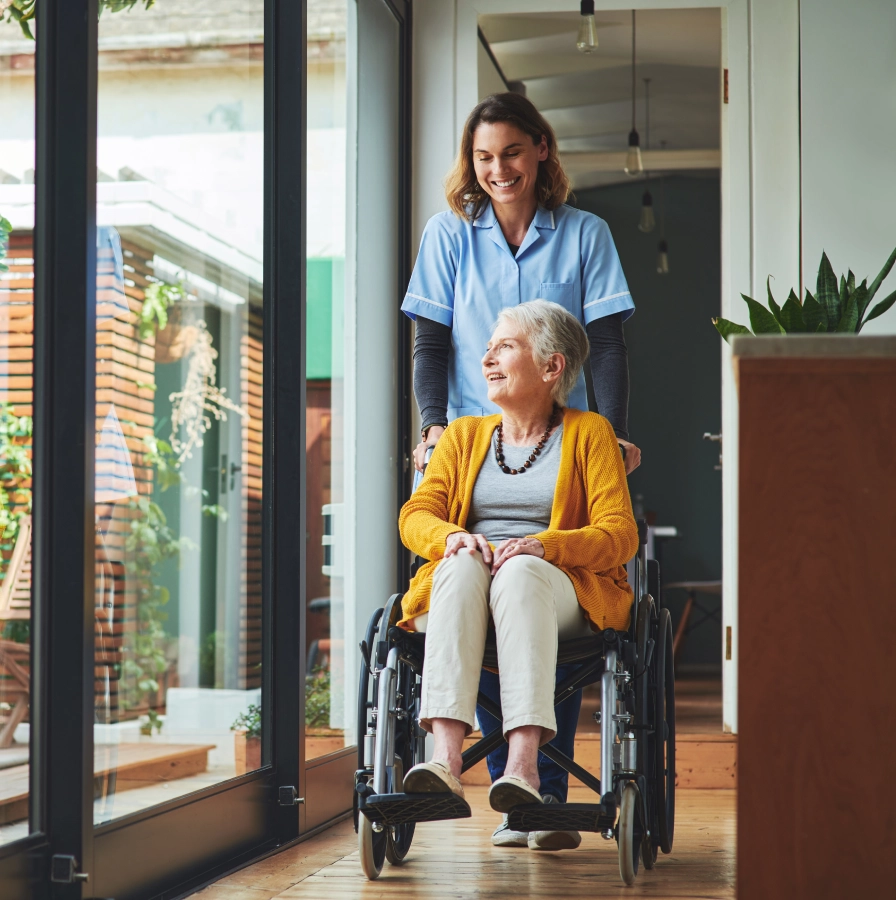 Caregiver pushing elderly woman in wheelchair.